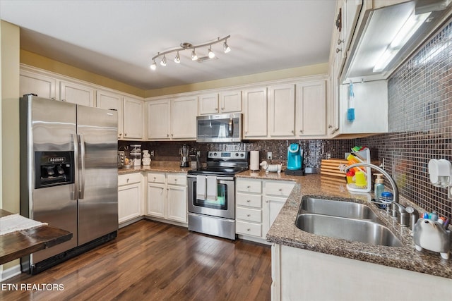 kitchen with dark wood finished floors, a sink, stainless steel appliances, and tasteful backsplash