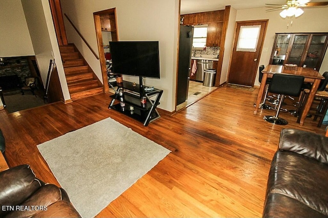 living room with a fireplace, stairway, wood finished floors, and ceiling fan