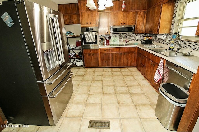 kitchen featuring a sink, stainless steel appliances, light countertops, backsplash, and visible vents