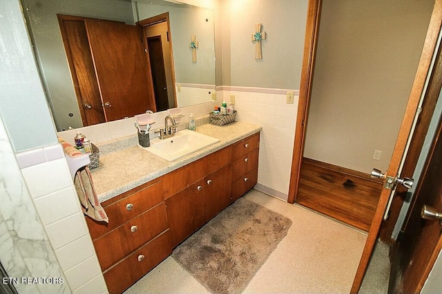 bathroom with tile walls, a wainscoted wall, and vanity