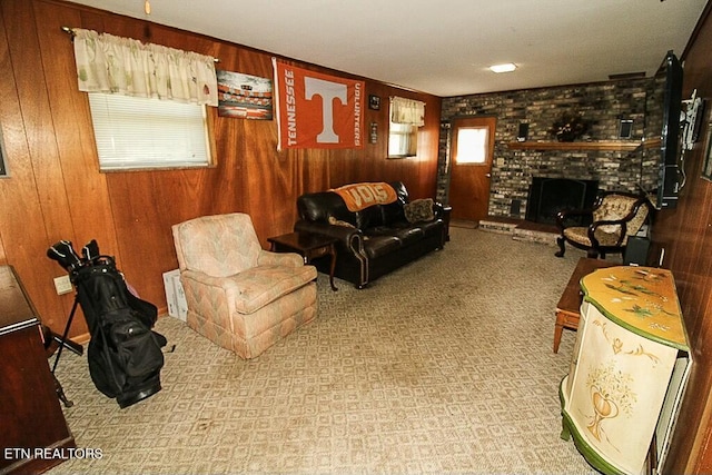 carpeted living room featuring wood walls and a fireplace