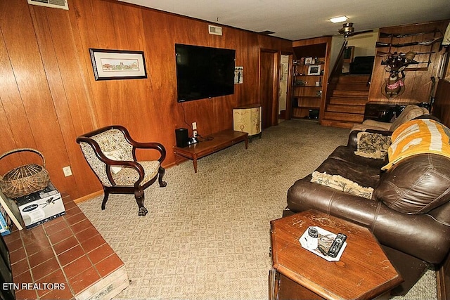 living area with stairway, baseboards, visible vents, and wooden walls