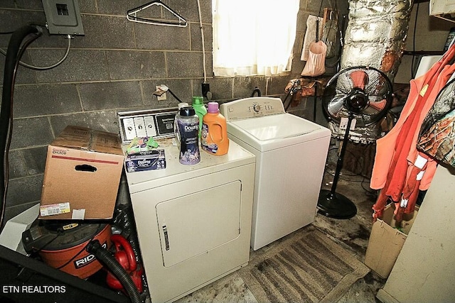 clothes washing area featuring concrete block wall, laundry area, and separate washer and dryer