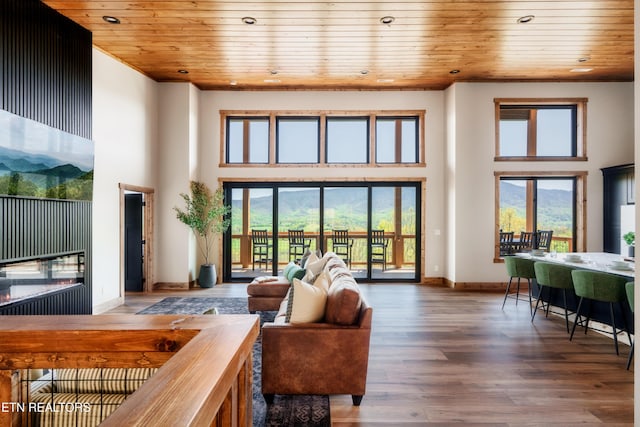 living room featuring wood ceiling, a towering ceiling, and a healthy amount of sunlight