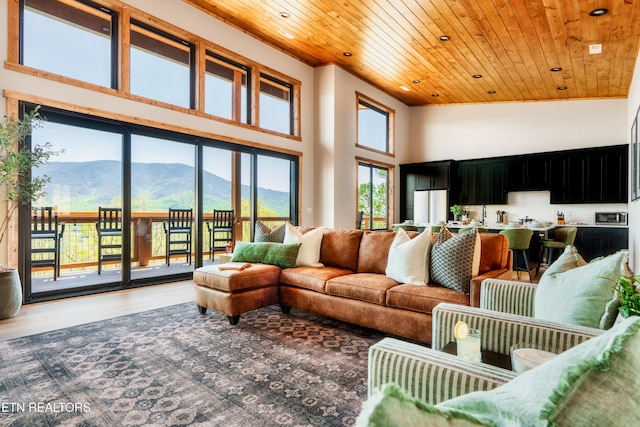 living area with a mountain view, wood ceiling, wood finished floors, and a towering ceiling
