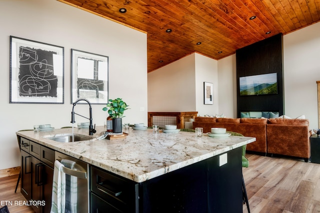 kitchen with a sink, lofted ceiling, wooden ceiling, and light wood-style floors