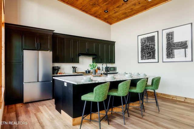 kitchen featuring freestanding refrigerator, under cabinet range hood, wooden ceiling, light wood finished floors, and vaulted ceiling