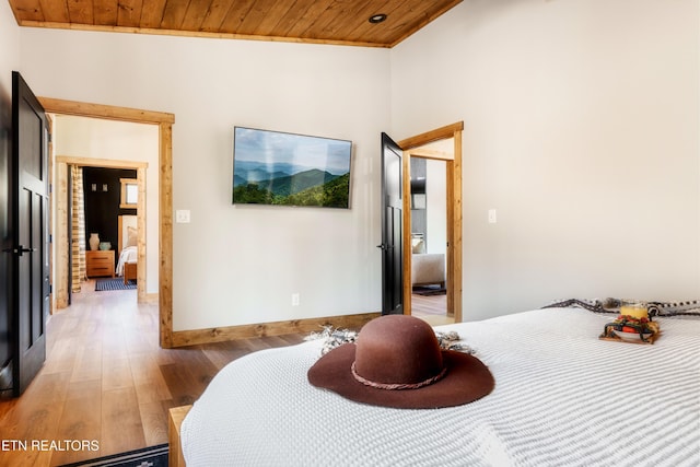 bedroom featuring light wood finished floors, crown molding, wood ceiling, and baseboards