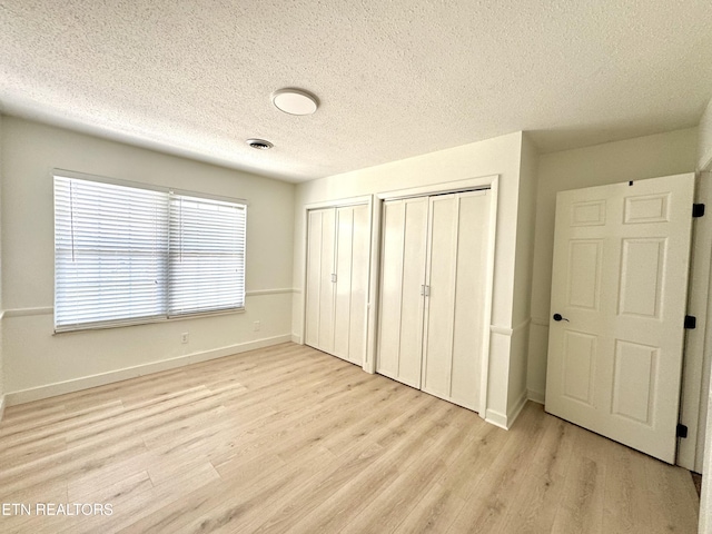 11709 Black Powder Dr, Knoxville, TN 37934 - unfurnished bedroom featuring light wood-type flooring, multiple closets, baseboards, and visible vents