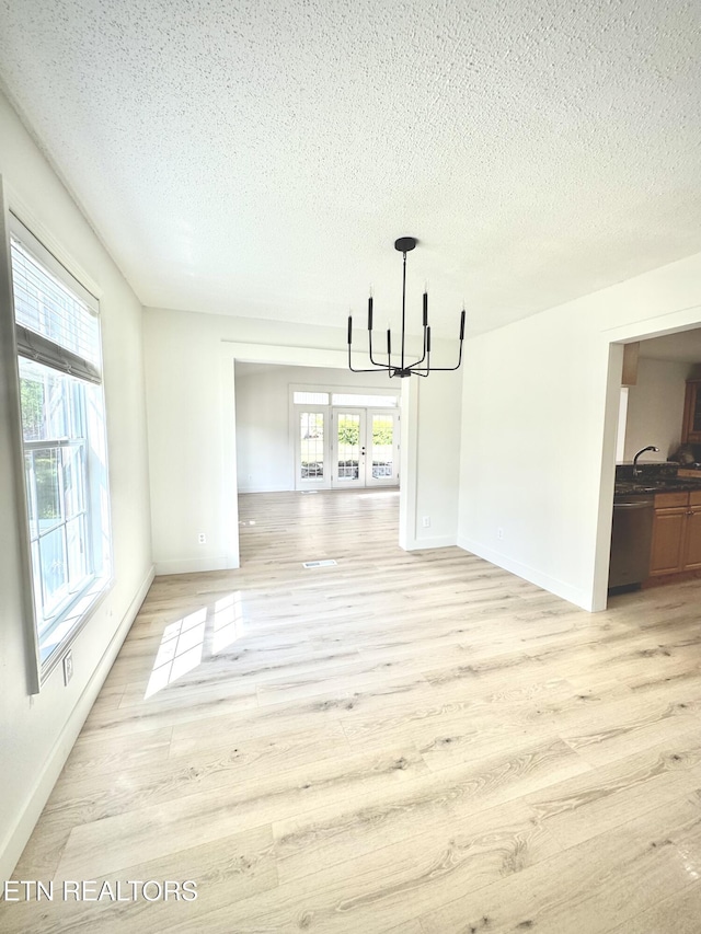 11709 Black Powder Dr, Knoxville, TN 37934 - unfurnished dining area featuring french doors, baseboards, light wood-style flooring, a textured ceiling, and a notable chandelier