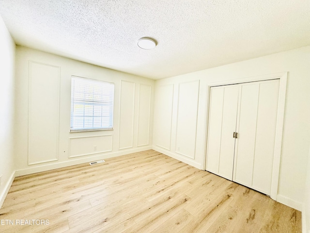 11709 Black Powder Dr, Knoxville, TN 37934 - unfurnished bedroom with light wood-style floors, a textured ceiling, a decorative wall, and visible vents