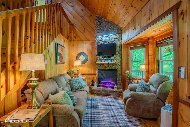 living area with a stone fireplace, wood finished floors, wooden ceiling, high vaulted ceiling, and wooden walls