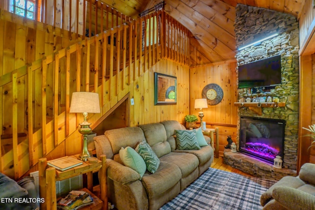 living room with high vaulted ceiling, wood-type flooring, wood walls, and a stone fireplace
