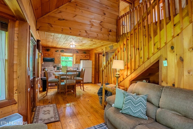 living area featuring stairs, wooden walls, wood ceiling, and light wood finished floors