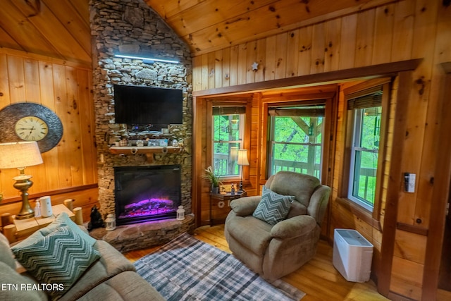 living area featuring a fireplace, wood walls, wood finished floors, wooden ceiling, and lofted ceiling