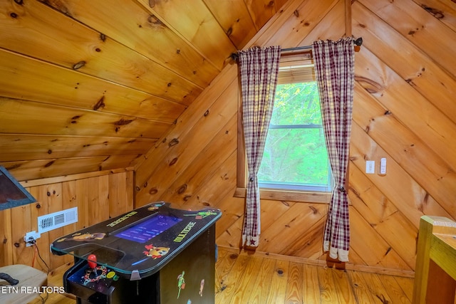 bonus room featuring wooden walls, vaulted ceiling, wood finished floors, and visible vents