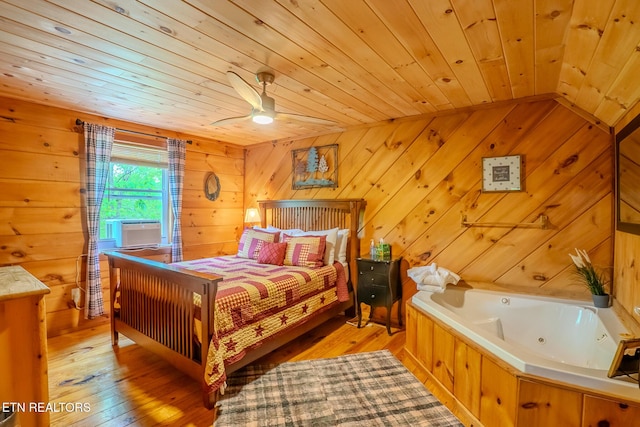 bedroom with light wood-style floors, wood ceiling, and wooden walls