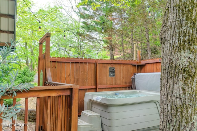 wooden deck with a hot tub and fence