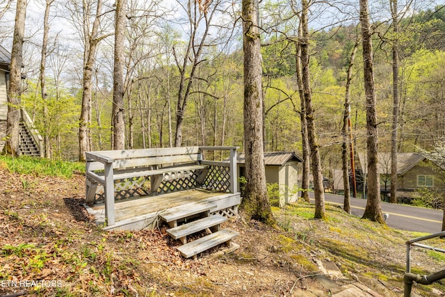 view of community with a deck and a wooded view