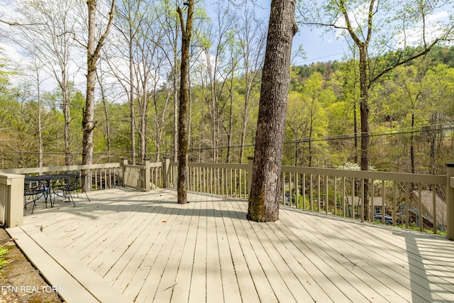 wooden deck with a wooded view and outdoor dining area