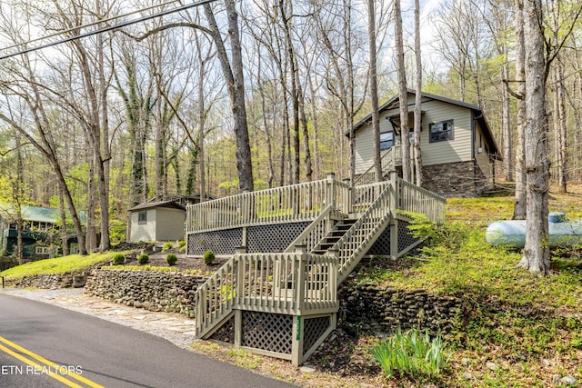 view of front of property featuring a deck, stairway, and stone siding