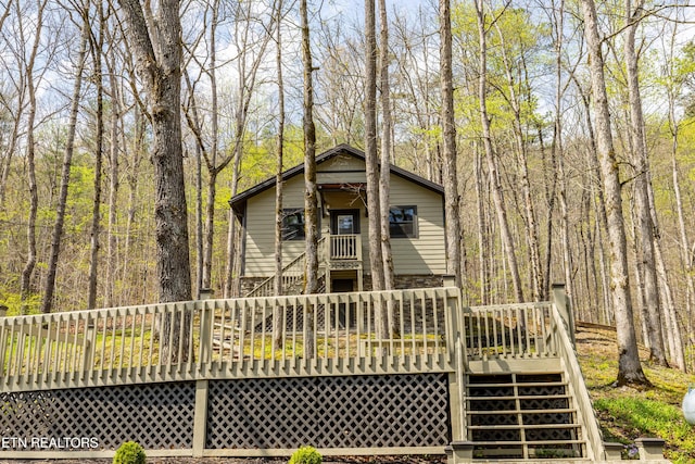 back of property featuring a deck, stairway, and a forest view