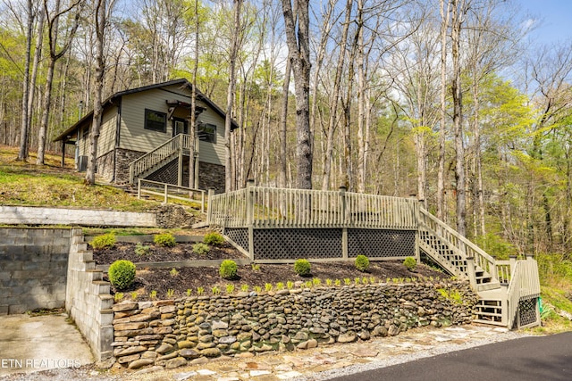 view of front of property with stairs, stone siding, and a deck