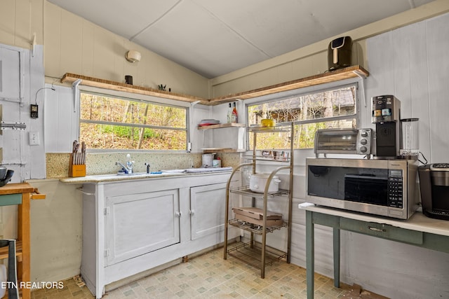 kitchen featuring a sink, light countertops, stainless steel microwave, lofted ceiling, and a toaster