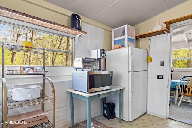 kitchen with a toaster, stainless steel microwave, and freestanding refrigerator