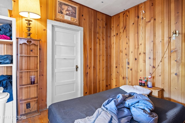 bedroom featuring wood finished floors and wooden walls