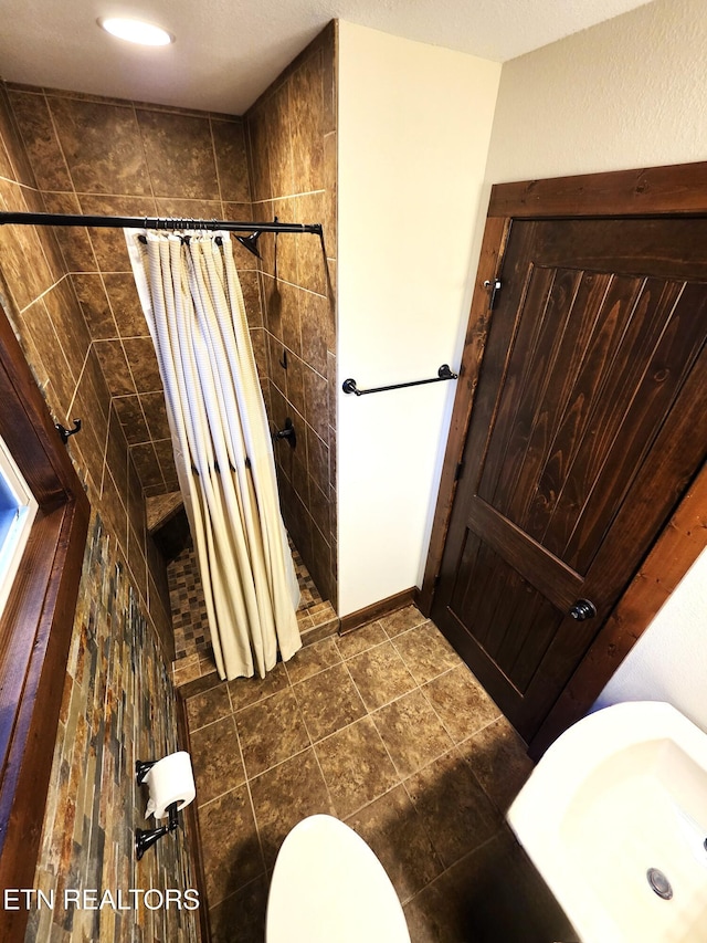 full bathroom featuring a tile shower and toilet
