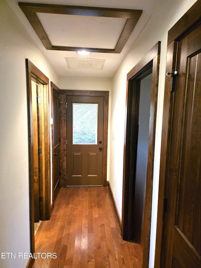 hall with baseboards, visible vents, and wood finished floors