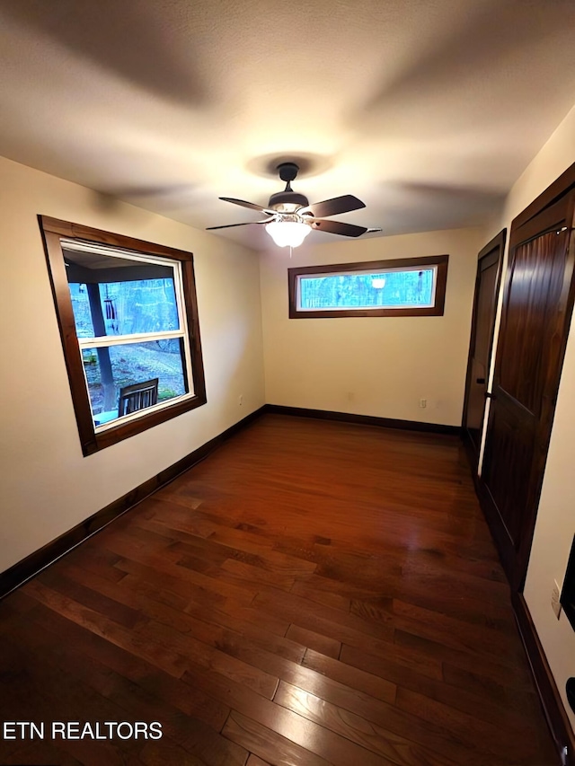 unfurnished bedroom with baseboards, a ceiling fan, and dark wood-style floors