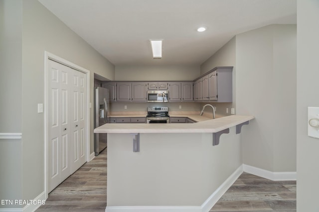 300 Willington Pl, Loudon, TN 37774 - kitchen with light wood-type flooring, gray cabinets, a peninsula, stainless steel appliances, and baseboards