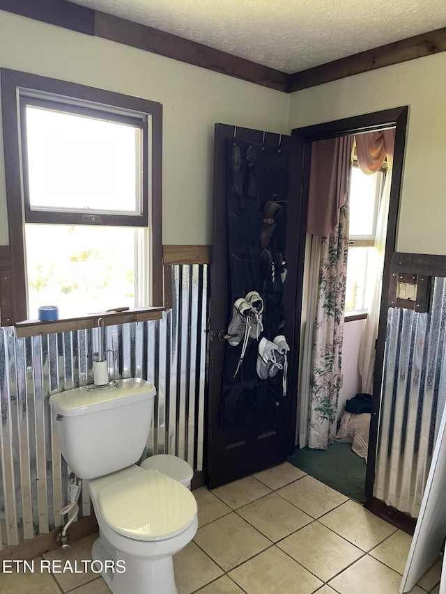 bathroom featuring a textured ceiling, tile patterned floors, and toilet