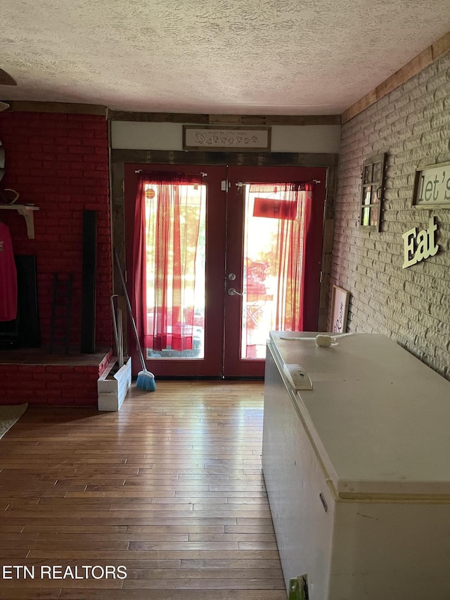 interior space featuring a textured ceiling, brick wall, and french doors