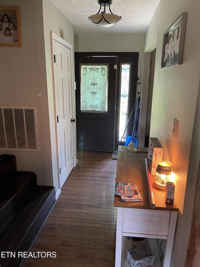 doorway to outside featuring stairs, dark wood-style flooring, a textured ceiling, and visible vents