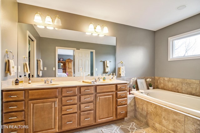 ensuite bathroom with a sink, double vanity, tile patterned floors, a garden tub, and ensuite bath