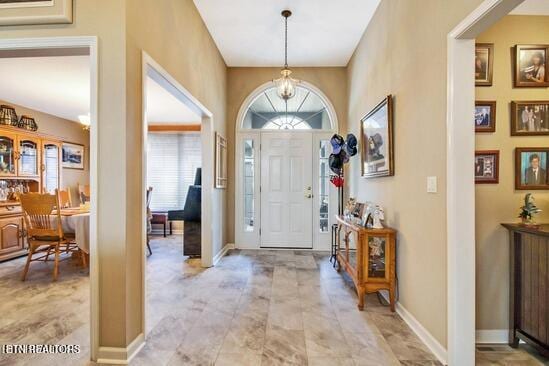 entryway with a chandelier and baseboards