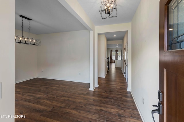 foyer entrance with baseboards, an inviting chandelier, and dark wood finished floors