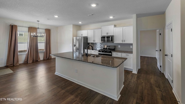 kitchen featuring a notable chandelier, appliances with stainless steel finishes, a sink, a kitchen island with sink, and visible vents