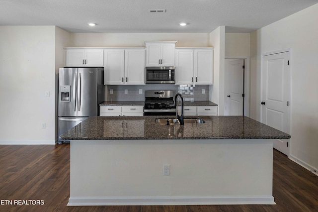 kitchen featuring white cabinets, a sink, stainless steel appliances, baseboards, and a center island with sink