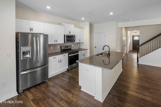 kitchen with a sink, stainless steel appliances, white cabinetry, decorative backsplash, and dark wood-type flooring