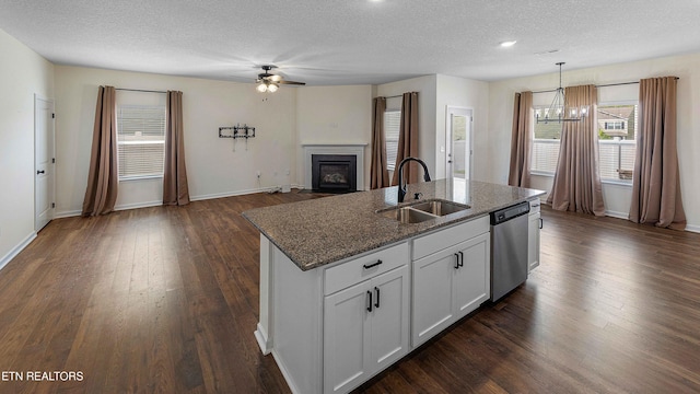 kitchen with a sink, a textured ceiling, ceiling fan with notable chandelier, a fireplace with flush hearth, and stainless steel dishwasher