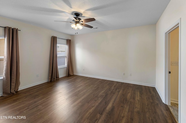 unfurnished room featuring a ceiling fan, baseboards, visible vents, and dark wood-type flooring