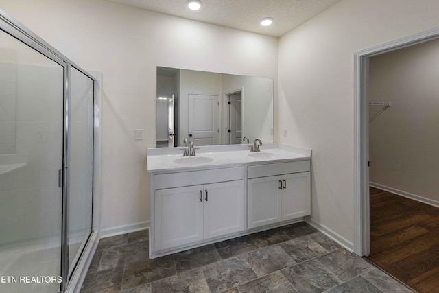 full bathroom with baseboards, a sink, and a shower stall