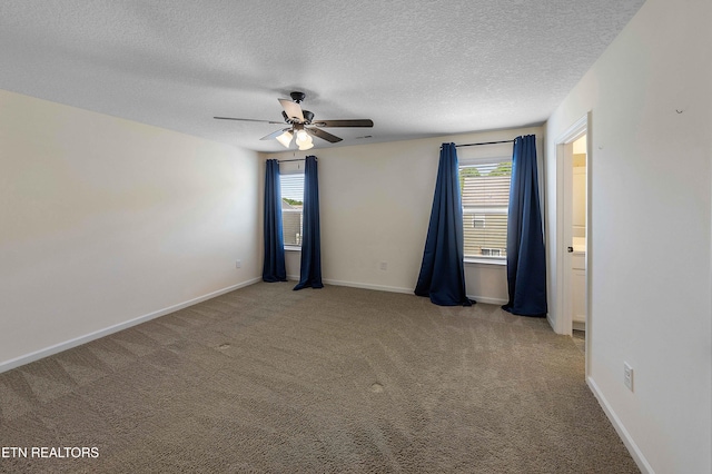 spare room featuring ceiling fan, carpet flooring, a textured ceiling, and a wealth of natural light