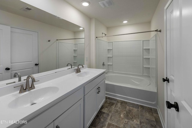 full bathroom with double vanity, stone finish flooring, visible vents, and a sink
