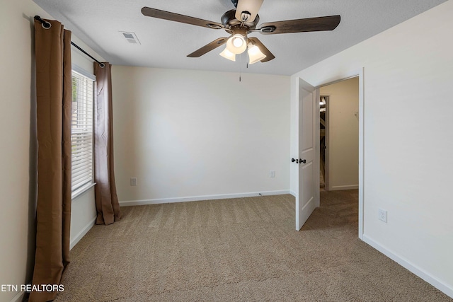 carpeted spare room featuring baseboards, ceiling fan, and visible vents