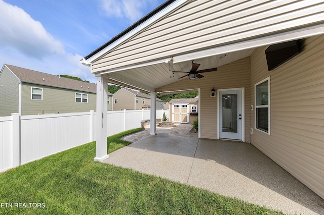 view of patio featuring ceiling fan, fence, an outdoor structure, and a storage unit